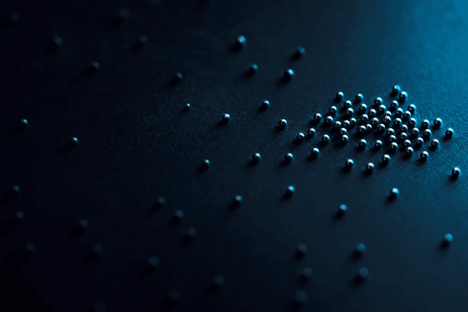 Scattered metal beads on a dark desk with a tight cluster pulling into sharp focus, signalling the move from long PPC keyword lists to focused themed clusters